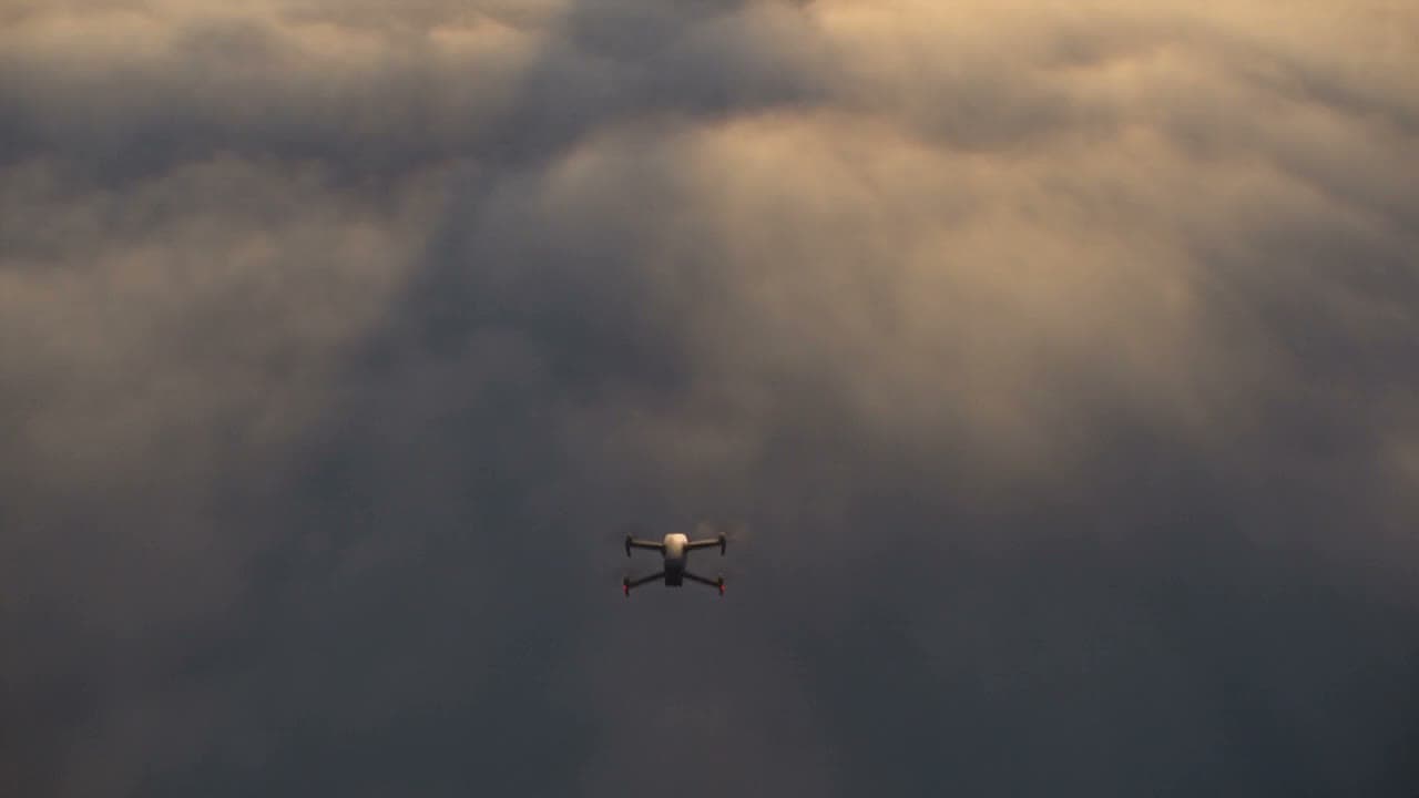 A small drone flying through grey clouds